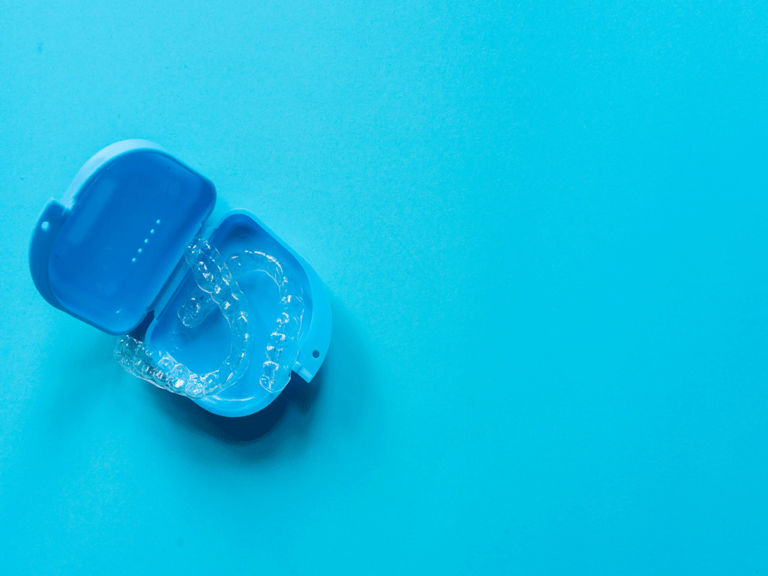 Photo of an Invisalign® clear aligners case holding two clear aligners with a blue background.